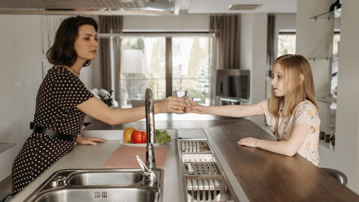 A mother and daughter bonding over a glass of water in a modern kitchen setting, illustrating aquatru vs waterdrop countertop ro
