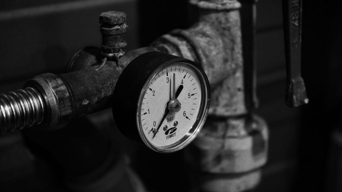 Close-up of a vintage pressure gauge on industrial pipes in monochrome, illustrating best clack water softener