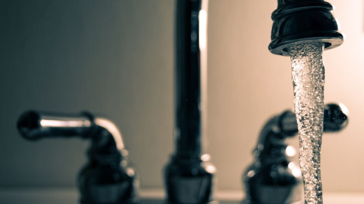 A detailed shot of water flowing from a steel faucet, ideal for themes on cleanliness or plumbi, illustrating best faucet water filter for hard water