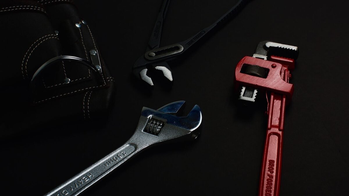 Close-up of various hand tools including wrenches and pliers on a dark surface, illustrating best fleck water softener