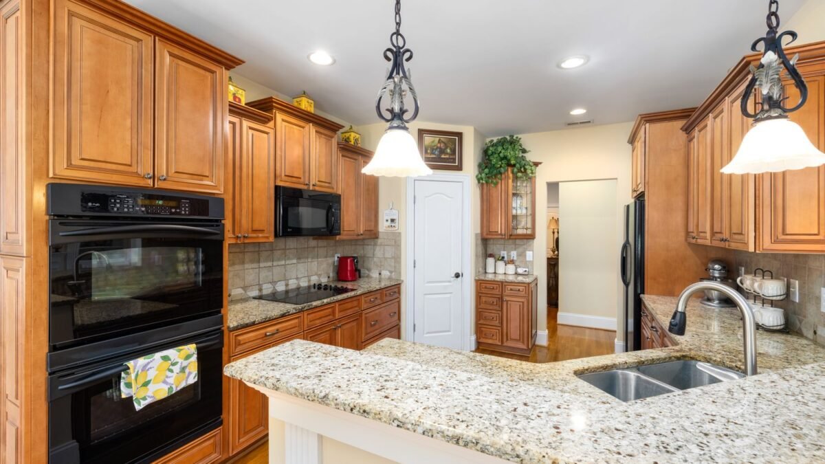 Spacious kitchen featuring wooden cabinets, granite countertops, and modern appliances, illustrating best granite safe hard water remover