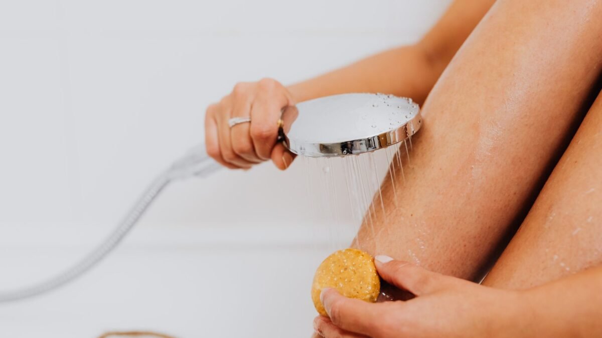 Close-up of hands holding soap and shower head, highlighting skincare routine, illustrating best handheld shower filter
