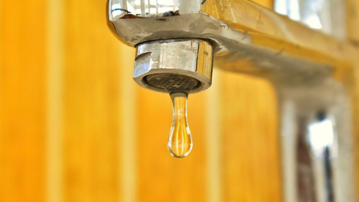 A close-up shot of a water droplet hanging from a stainless steel faucet, highlighting surface , illustrating best high efficiency water softener