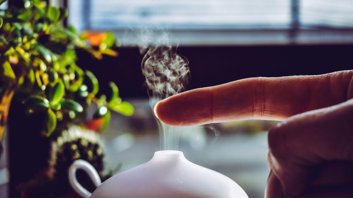 A hand touches mist rising from a diffuser, creating a relaxing ambiance indoors, illustrating best humidifier demineralization cartridge