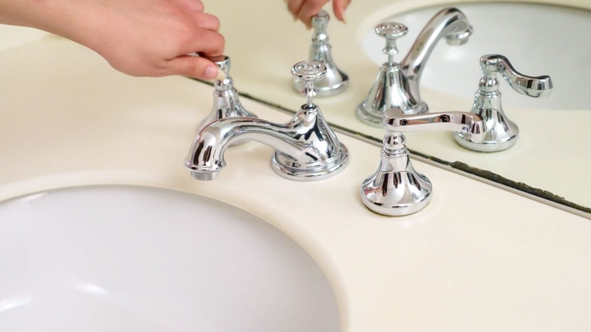 Close-up of a hand adjusting a chrome faucet in a modern bathroom interior, illustrating best on demand water softener