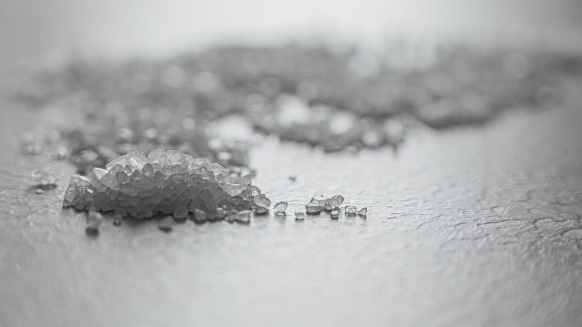 Detailed shot of coarse rock salt scattered on a textured surface, illustrating best potassium chloride water softener salt