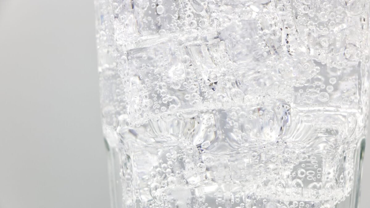 Refreshing sparkling water with ice cubes in a clear glass, close-up view, illustrating best remineralization filter