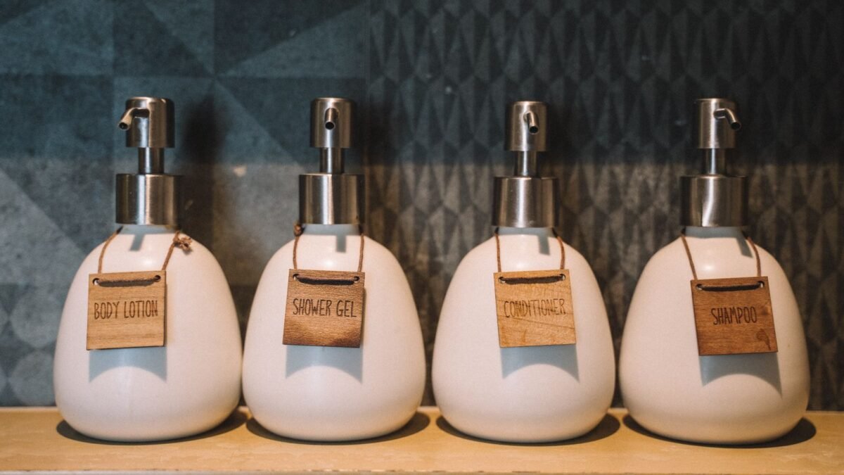 Elegant pump bottles holding bath essentials like lotion, gel, and more on a wooden shelf, illustrating best shampoo for hard water