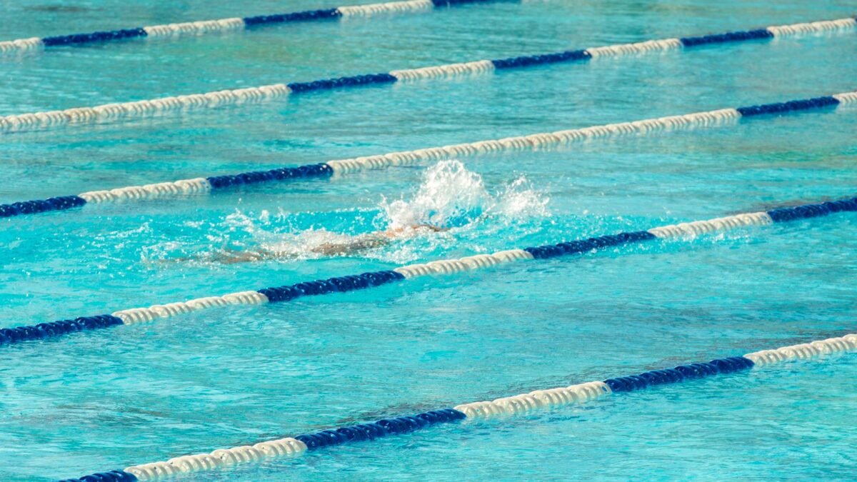 Swimmer in action making a splash in clear blue swimming pool lanes, illustrating best shower filter for chloramine