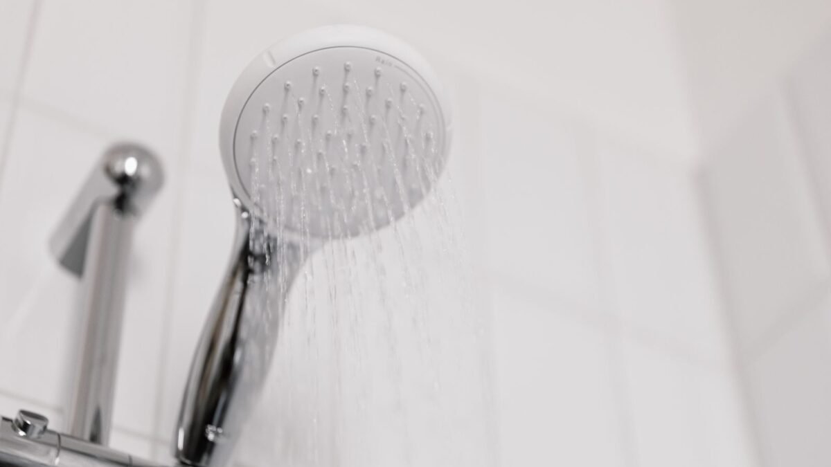 Water streaming from a chrome shower head, where a shower filter for hard water attaches