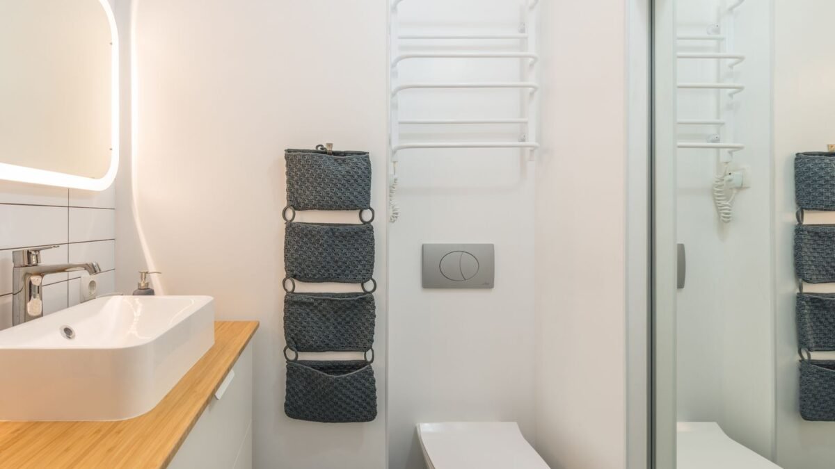 Small modern bathroom with ceramic toilet bowl and sink under illuminated mirror in modern apar, illustrating best shower filter for rental apartment