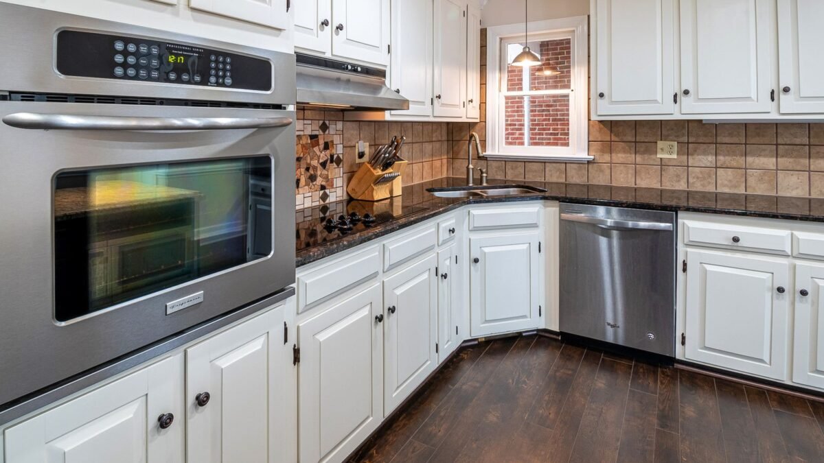 Spacious kitchen featuring white cabinets, stainless steel appliances, and wooden flooring, illustrating best under sink water filter for hard water