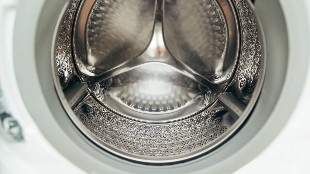 Detailed view of a clean, modern washing machine drum, showcasing shiny stainless steel interio, illustrating best washing machine cleaner