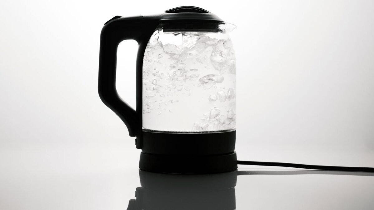 A sleek electric kettle boiling water, captured on a reflective white surface, illustrating best water filter for kettle scale
