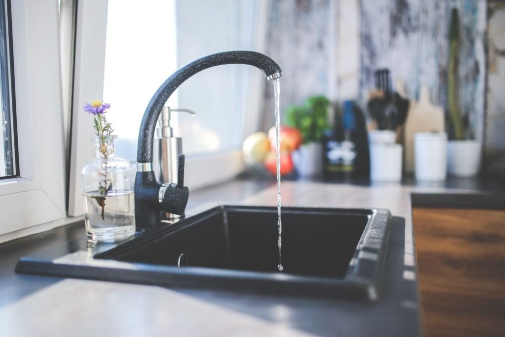 Kitchen faucet running hard water into a sink in a busy family home