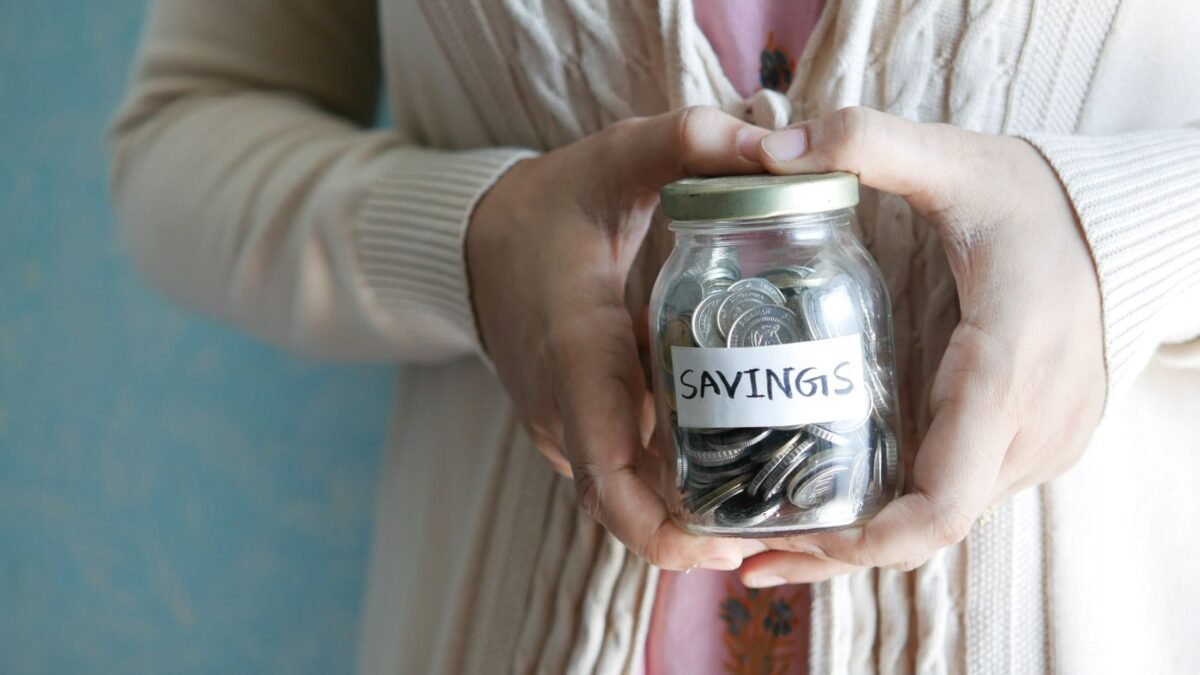 Woman holding a jar labeled 'savings' filled with coins, representing financial savings, illustrating best water softener under 1000