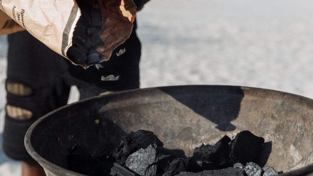 Detailed image of charcoal poured from a bag into a grilling basin outdoors, illustrating best water softener with carbon filter
