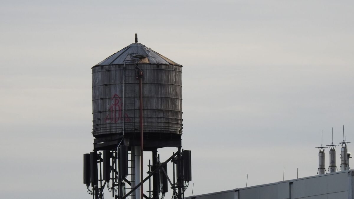 A metal water tank stands prominently on a rooftop against a clear sky, illustrating best whole house water filter for chloramine