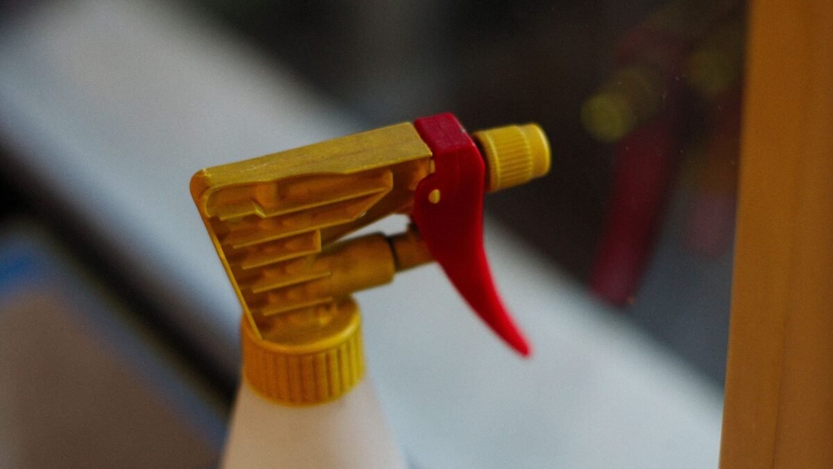 Detailed view of a yellow and red spray bottle nozzle in focus, illustrating clr vs lime a way