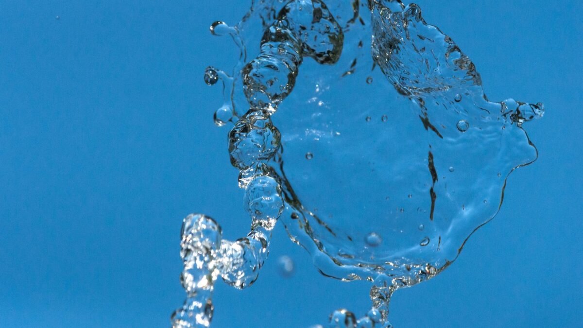 Detailed capture of water droplets in motion against a blue background, illustrating crystal quest water softener review