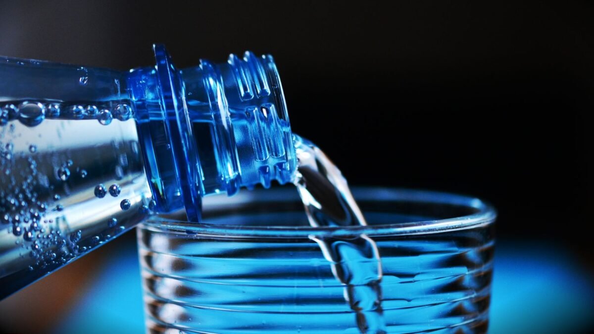 Close-up of sparkling water being poured from a bottle into a glass with bubbles visible, illustrating ecowater vs rainsoft