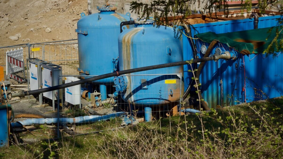 Outdoor industrial water filtration plant with large blue tanks under sunlight, illustrating express water whole house filter review