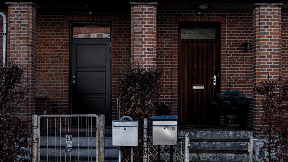 A brick building facade with two distinct doorways and metal fencing, featuring mailboxes and u, illustrating home master whole house filter review
