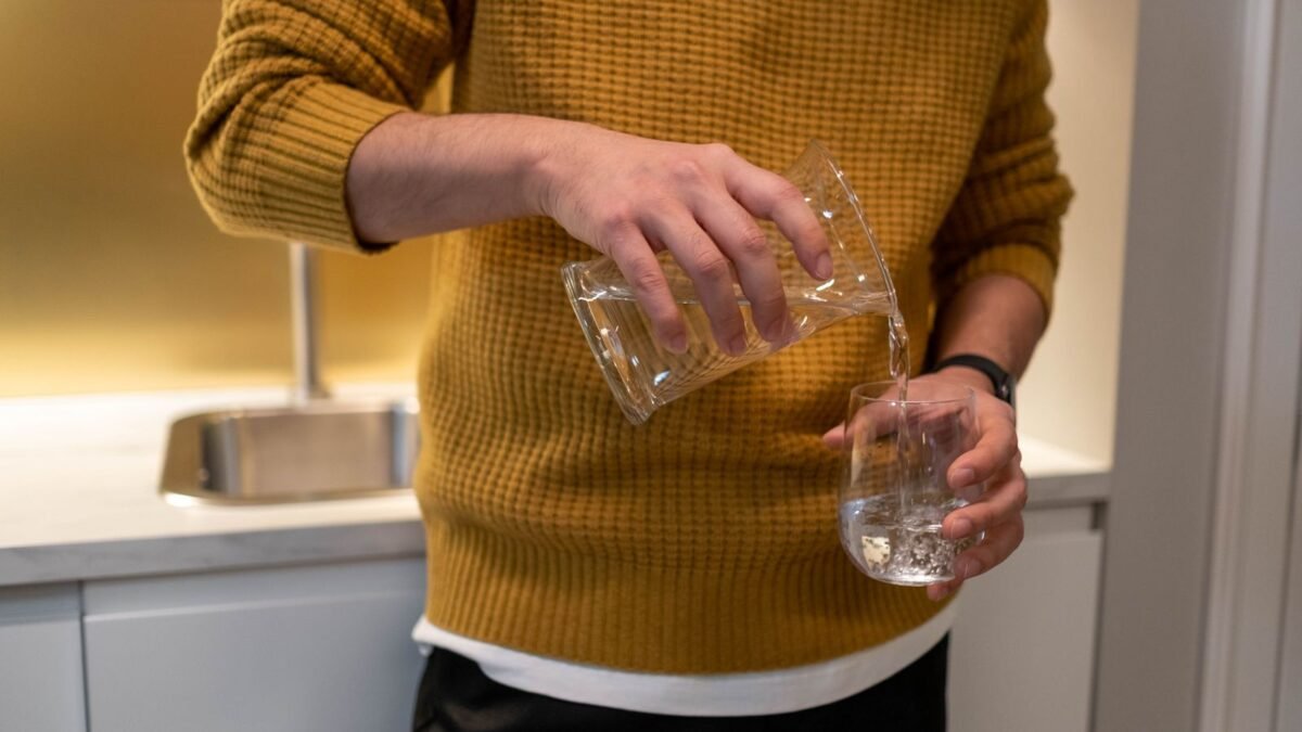 Close-up of individual pouring water into glass in a modern kitchen, illustrating ispring wgb32b review