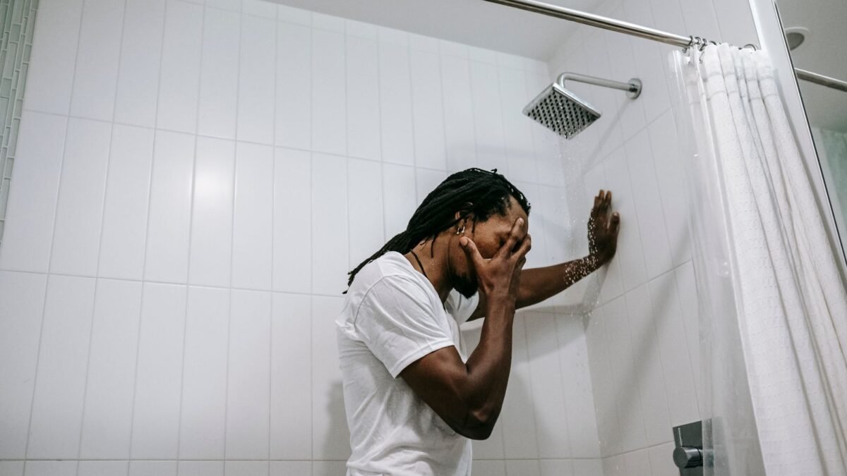 Side view depressed preoccupied African American male in white shirt covering face with hand in, illustrating jolie vs aquabliss