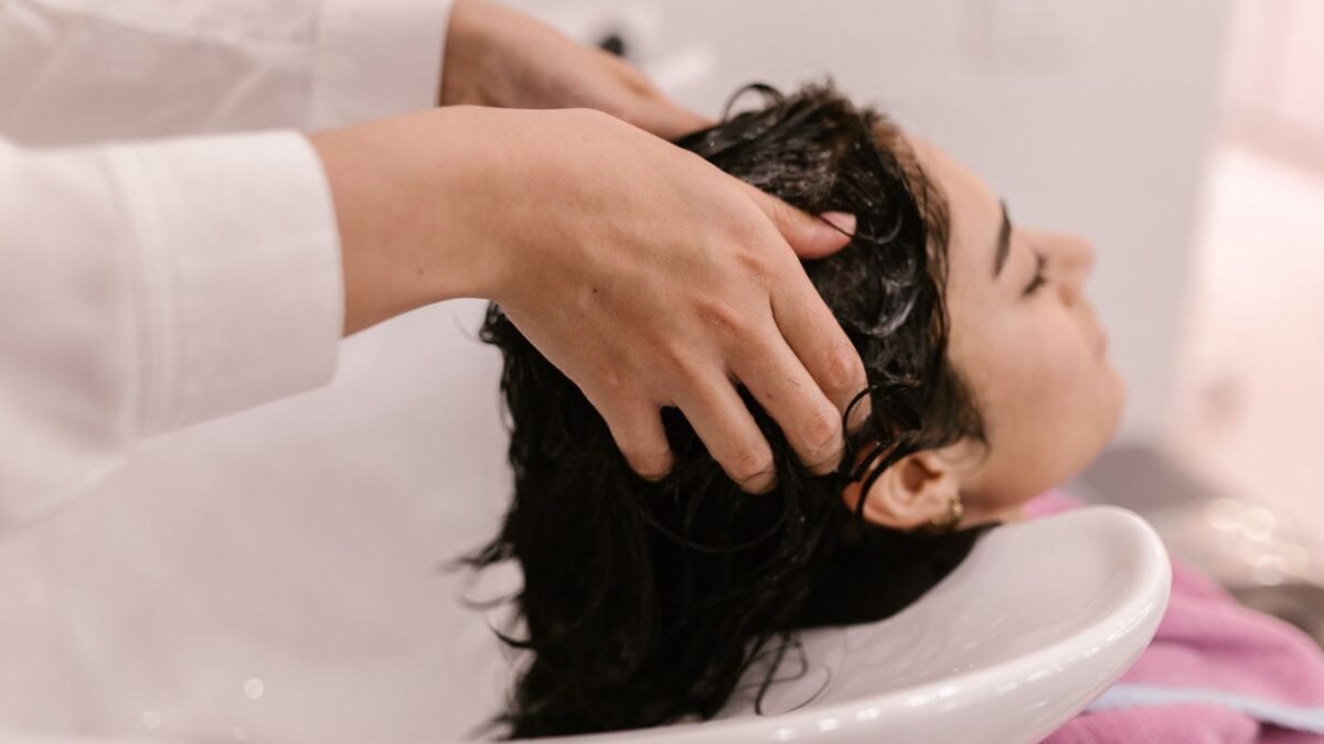 A woman enjoys a relaxing hair wash at a salon. Captured in a cozy indoor setting, illustrating jolie vs hello klean