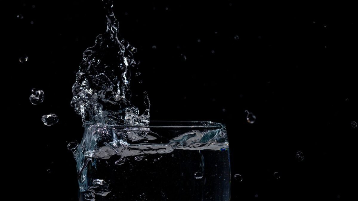 Close-up of water splashing in a glass against a black background, illustrating pelican vs aquasana