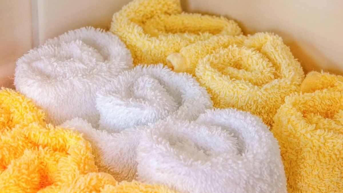 Neatly arranged rolled white and yellow towels in a bathroom setting for hygiene and decor, illustrating softpro elite review
